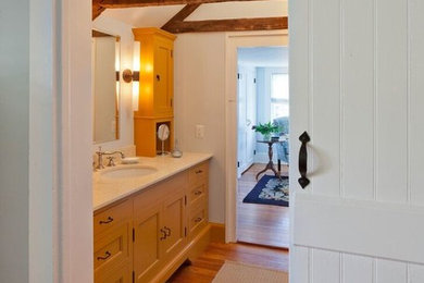 Großes Klassisches Duschbad mit Schrankfronten im Shaker-Stil, gelben Schränken, weißer Wandfarbe, braunem Holzboden, Einbauwaschbecken und Mineralwerkstoff-Waschtisch in New York