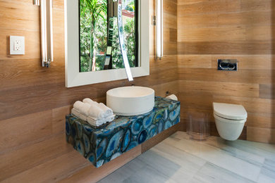 マイアミにある広いコンテンポラリースタイルのおしゃれなバスルーム (浴槽なし) (ベッセル式洗面器、壁掛け式トイレ、白いタイル、茶色い壁、大理石の床、オニキスの洗面台、グレーの床、青い洗面カウンター) の写真