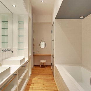 Idées déco pour une grand salle de bain principale contemporaine avec un placard sans porte, une baignoire posée, un carrelage métro, un mur blanc, une vasque, un carrelage blanc et un sol en bois brun.