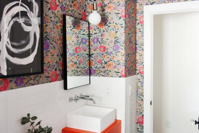 Example of a small eclectic 3/4 white tile and ceramic tile ceramic tile, black floor, single-sink and wallpaper bathroom design in Phoenix with flat-panel cabinets, orange cabinets, multicolored walls, a vessel sink, laminate countertops, orange countertops and a freestanding vanity