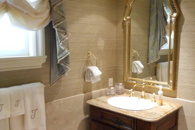 Ispirazione per una stanza da bagno tradizionale di medie dimensioni con lavabo da incasso, consolle stile comò, ante in legno scuro, top in marmo, piastrelle beige, piastrelle in pietra, pareti beige e pavimento in travertino