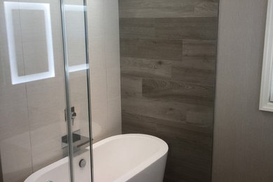 Inredning av ett modernt mellanstort en-suite badrum, med släta luckor, grå skåp, ett fristående badkar, en öppen dusch, en toalettstol med hel cisternkåpa, keramikplattor, grå väggar, betonggolv och ett nedsänkt handfat