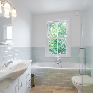 Small classic family bathroom in London with flat-panel cabinets, white cabinets, a built-in bath, grey tiles, ceramic tiles, white walls, porcelain flooring, brown floors, a hinged door and a console sink.