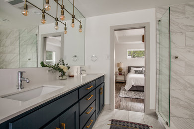This is an example of a medium sized traditional ensuite wet room bathroom in Dallas with shaker cabinets, blue cabinets, a freestanding bath, a two-piece toilet, grey tiles, porcelain tiles, white walls, porcelain flooring, a submerged sink, engineered stone worktops, grey floors, a hinged door and white worktops.