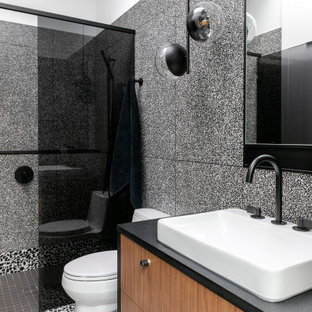 Aménagement d'une petit douche en alcôve principale contemporaine avec un placard à porte plane, un WC à poser, un carrelage noir et blanc, des carreaux de porcelaine, un mur blanc, une vasque, un plan de toilette en granite, un sol noir, une cabine de douche à porte battante, un plan de toilette noir, meuble simple vasque, meuble-lavabo suspendu, des portes de placard en bois brun et un sol en terrazzo.