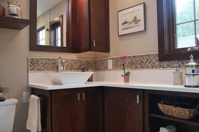 Example of a small transitional master gray tile and ceramic tile ceramic tile corner shower design in New York with shaker cabinets, dark wood cabinets, a two-piece toilet, beige walls, a vessel sink and quartz countertops