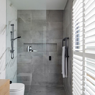 Contemporary bathroom in Other with flat-panel cabinets, medium wood cabinets, a curbless shower, a wall-mount toilet, gray tile, white tile, white walls, wood benchtops, grey floor, an open shower and brown benchtops.
