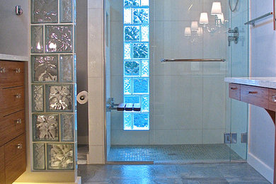 小さなモダンスタイルのおしゃれなマスターバスルーム (アンダーカウンター洗面器、フラットパネル扉のキャビネット、中間色木目調キャビネット、クオーツストーンの洗面台、バリアフリー、分離型トイレ、白いタイル、ガラスタイル、グレーの壁、リノリウムの床) の写真