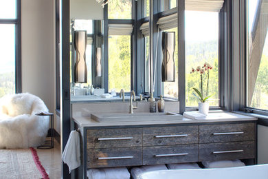 Diseño de cuarto de baño principal minimalista con bañera exenta, ducha doble, suelo de cemento y ducha con puerta con bisagras