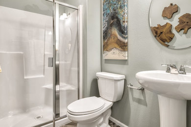 シアトルにあるお手頃価格の中くらいなエクレクティックスタイルのおしゃれなバスルーム (浴槽なし) (白いキャビネット、アルコーブ型シャワー、一体型トイレ	、グレーの壁、ラミネートの床、ペデスタルシンク、グレーの床、開き戸のシャワー) の写真