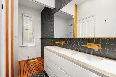 Modelo de cuarto de baño actual con baldosas y/o azulejos blancas y negros, paredes blancas y encimeras beige