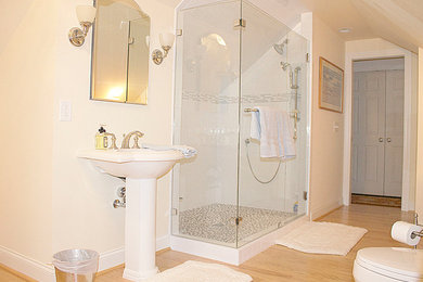 Diseño de cuarto de baño tradicional grande con lavabo con pedestal, ducha abierta, sanitario de una pieza, baldosas y/o azulejos grises, baldosas y/o azulejos de cerámica, paredes beige, suelo de madera clara y aseo y ducha
