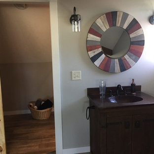 Example of a mid-sized mountain style 3/4 brown floor and medium tone wood floor bathroom design in Milwaukee with gray walls, furniture-like cabinets, dark wood cabinets, solid surface countertops, a two-piece toilet and an integrated sink