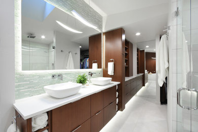 Стильный дизайн: большая главная ванная комната в современном стиле с плоскими фасадами, темными деревянными фасадами, отдельно стоящей ванной, двойным душем, унитазом-моноблоком, белой плиткой, керамогранитной плиткой, белыми стенами, полом из керамогранита, настольной раковиной, столешницей из искусственного кварца, белым полом, душем с распашными дверями, белой столешницей, нишей, тумбой под две раковины, встроенной тумбой и деревянными стенами - последний тренд
