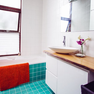 Esempio di una stanza da bagno con doccia tropicale di medie dimensioni con lavabo integrato, ante a filo, ante bianche, top in superficie solida, vasca ad angolo, doccia ad angolo, WC sospeso, piastrelle blu, piastrelle di vetro, pareti bianche e pavimento con piastrelle in ceramica