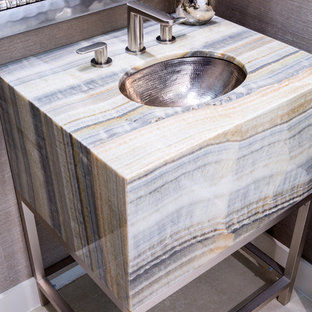 Bild på ett mellanstort funkis badrum för barn, med ett undermonterad handfat, öppna hyllor, grå skåp, bänkskiva i onyx, en toalettstol med hel cisternkåpa, beige kakel, stenkakel, beige väggar och klinkergolv i porslin