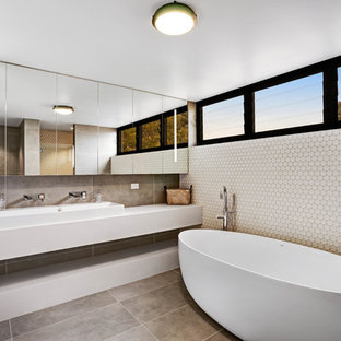 Mid-sized contemporary 3/4 bathroom in Central Coast with a freestanding tub, engineered quartz benchtops, flat-panel cabinets, a trough sink, grey floor and white benchtops.