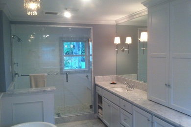 Inredning av ett klassiskt mellanstort en-suite badrum, med ett undermonterad handfat, skåp i shakerstil, vita skåp, marmorbänkskiva, ett fristående badkar, en öppen dusch, en toalettstol med separat cisternkåpa, vit kakel, stenkakel, grå väggar och marmorgolv
