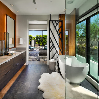 Large trendy master brown floor freestanding bathtub photo in Phoenix with flat-panel cabinets, quartz countertops, gray countertops, an undermount sink, dark wood cabinets and gray walls