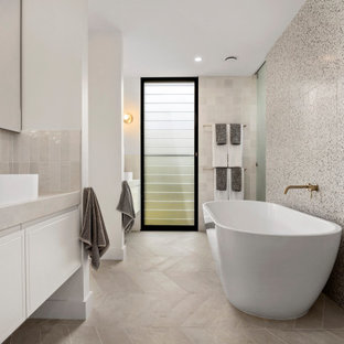 Design ideas for a beach style master bathroom in Sydney with flat-panel cabinets, white cabinets, a freestanding tub, beige tile, black and white tile, white walls, a vessel sink, beige floor and beige benchtops.