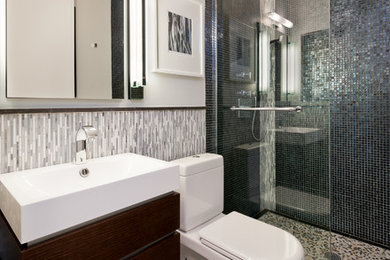 Imagen de cuarto de baño principal contemporáneo pequeño con lavabo suspendido, armarios con paneles lisos, puertas de armario de madera en tonos medios, ducha abierta, sanitario de una pieza, baldosas y/o azulejos negros, baldosas y/o azulejos en mosaico, paredes grises y suelo de mármol