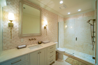 マイアミにある中くらいなトランジショナルスタイルのおしゃれなバスルーム (浴槽なし) (インセット扉のキャビネット、白いキャビネット、アルコーブ型シャワー、分離型トイレ、ベージュのタイル、セラミックタイル、ベージュの壁、トラバーチンの床、アンダーカウンター洗面器、ベージュの床、開き戸のシャワー、ベージュのカウンター) の写真