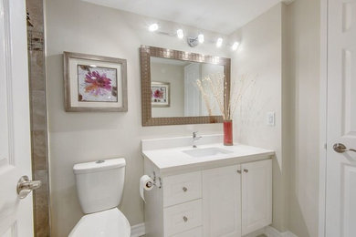 トロントにある中くらいなトラディショナルスタイルのおしゃれなバスルーム (浴槽なし) (レイズドパネル扉のキャビネット、白いキャビネット、一体型トイレ	、ベージュの壁、アンダーカウンター洗面器) の写真