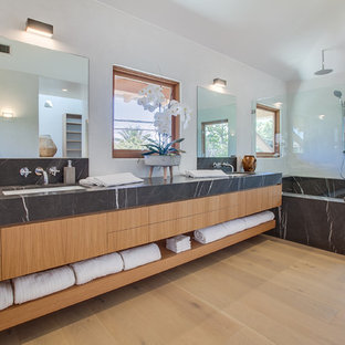 Bathroom - tropical master light wood floor and beige floor bathroom idea in Los Angeles with flat-panel cabinets, medium tone wood cabinets, white walls, an undermount sink and black countertops