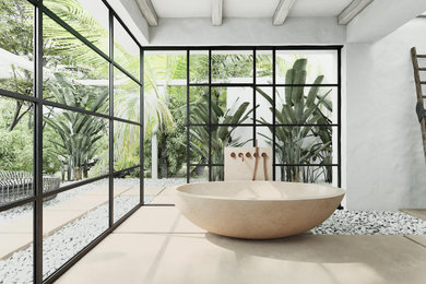 Modelo de cuarto de baño tropical con bañera exenta, suelo de mármol y suelo beige