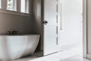 Imagen de cuarto de baño principal clásico renovado de tamaño medio con bañera exenta, baldosas y/o azulejos de mármol, paredes grises, suelo de baldosas de cerámica y suelo blanco