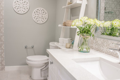 Bathroom - transitional gray tile and porcelain tile porcelain tile, gray floor and single-sink bathroom idea in Calgary with shaker cabinets, white cabinets, a two-piece toilet, gray walls, an undermount sink, quartz countertops and white countertops