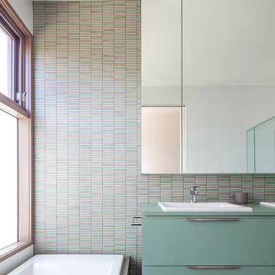 Trendy master black floor drop-in bathtub photo in Melbourne with flat-panel cabinets, green cabinets, multicolored walls and a drop-in sink