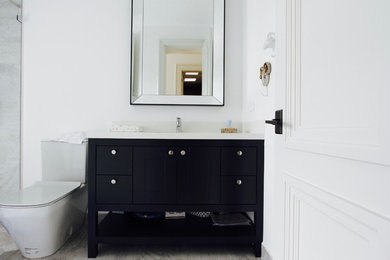 他の地域にあるコンテンポラリースタイルのおしゃれな浴室 (家具調キャビネット、黒いキャビネット、白い壁、磁器タイルの床、クオーツストーンの洗面台) の写真