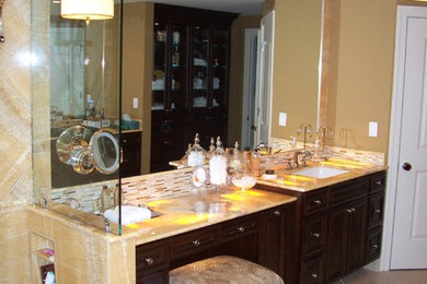 Transitional beige tile and stone tile bathroom photo in Other with raised-panel cabinets, dark wood cabinets and onyx countertops