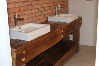 Diseño de cuarto de baño principal rústico grande con armarios con puertas mallorquinas, puertas de armario de madera oscura, lavabo sobreencimera y encimera de madera