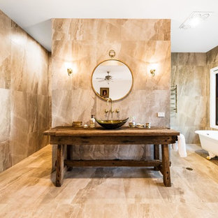 Inspiration for a country 3/4 bathroom in Other with a claw-foot tub, beige tile, beige walls, wood benchtops, beige floor and a vessel sink.