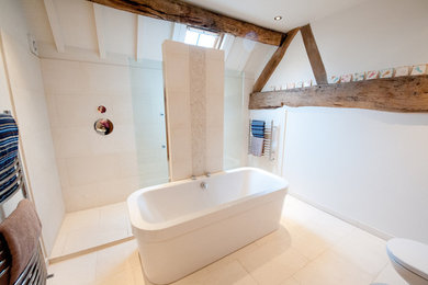 На фото: детская ванная комната среднего размера в современном стиле с белыми фасадами, отдельно стоящей ванной, открытым душем, инсталляцией, бежевой плиткой, каменной плиткой, белыми стенами, полом из известняка и подвесной раковиной