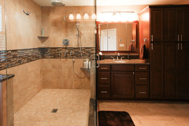 Corner shower - large transitional master beige tile and porcelain tile porcelain tile and beige floor corner shower idea in Philadelphia with shaker cabinets, dark wood cabinets, granite countertops, a two-piece toilet, beige walls, an undermount sink, a hinged shower door and brown countertops