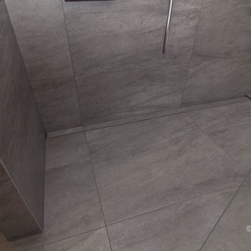 Barrier-free bathroom with large grey tile and floating double vanity
