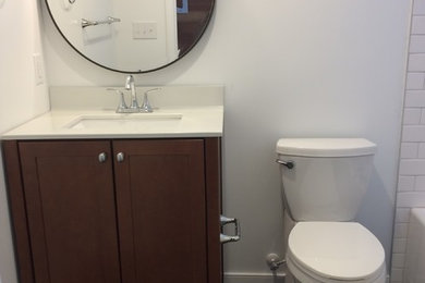 Example of a small trendy white tile and subway tile slate floor tub/shower combo design in Other with shaker cabinets, medium tone wood cabinets, a two-piece toilet, white walls, an undermount sink and solid surface countertops