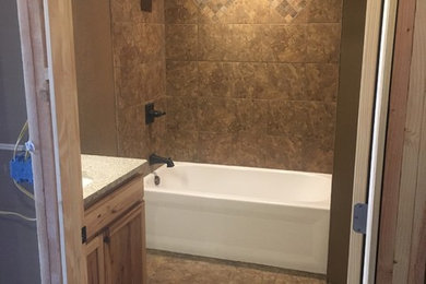Example of a mid-sized mountain style master brown tile and ceramic tile ceramic tile and brown floor bathroom design in Other with raised-panel cabinets, light wood cabinets, a two-piece toilet, green walls, an integrated sink and granite countertops