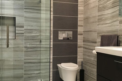 Diseño de cuarto de baño contemporáneo de tamaño medio con puertas de armario de madera en tonos medios, ducha esquinera, sanitario de pared, paredes grises y suelo de azulejos de cemento