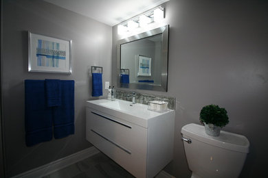 Example of a mid-sized trendy kids' gray tile and glass sheet ceramic tile and white floor alcove bathtub design in Ottawa with flat-panel cabinets, white cabinets, a two-piece toilet, gray walls, an integrated sink, solid surface countertops and white countertops