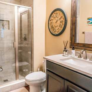 Foto de cuarto de baño con ducha, ecléctico, pequeño, con armarios con paneles empotrados, puertas de armario marrones, ducha empotrada, sanitario de dos piezas, baldosas y/o azulejos grises, baldosas y/o azulejos de cerámica, paredes beige, suelo de madera en tonos medios, lavabo bajoencimera, encimera de cuarcita, suelo marrón, ducha con puerta con bisagras y encimeras blancas