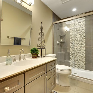 Bathroom - small transitional 3/4 gray tile and porcelain tile ceramic tile and beige floor bathroom idea in Minneapolis with gray cabinets, beige walls, solid surface countertops, a two-piece toilet, an integrated sink and recessed-panel cabinets