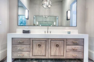 This is an example of a large contemporary bathroom in Houston with raised-panel cabinets, light wood cabinets, black tiles, stone tiles, grey walls, marble flooring, a submerged sink and engineered stone worktops.