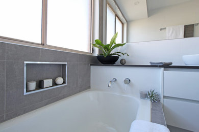 Design ideas for a small contemporary family bathroom in Brisbane with flat-panel cabinets, white cabinets, a built-in bath, a corner shower, a two-piece toilet, white tiles, ceramic tiles, white walls, terracotta flooring, a vessel sink, engineered stone worktops, grey floors, a hinged door and black worktops.