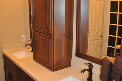 Inredning av ett klassiskt mellanstort en-suite badrum, med luckor med upphöjd panel, skåp i mellenmörkt trä, bänkskiva i akrylsten, en toalettstol med hel cisternkåpa, beige kakel, stenkakel, beige väggar, mellanmörkt trägolv, ett undermonterad handfat, dusch med gångjärnsdörr och en hörndusch