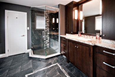 Photo of a large classic ensuite bathroom in Toronto with flat-panel cabinets, dark wood cabinets, a corner shower, grey walls, porcelain flooring, a submerged sink, black floors and a hinged door.