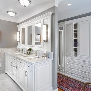 Modelo de cuarto de baño clásico con lavabo bajoencimera, armarios con paneles con relieve, puertas de armario blancas y baldosas y/o azulejos blancos